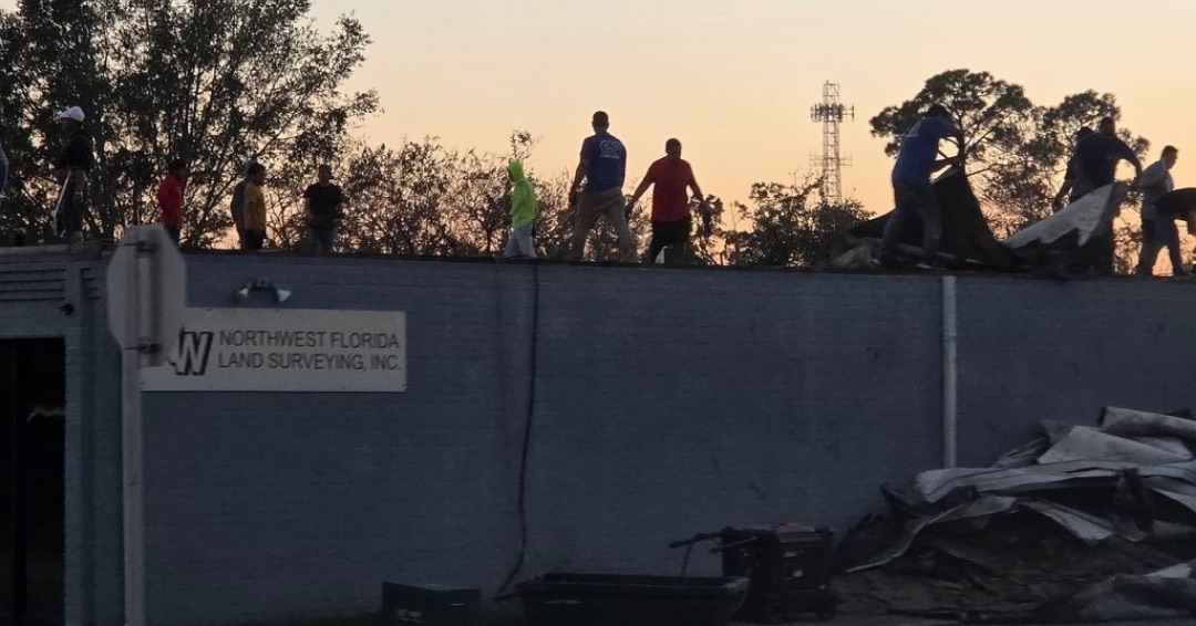 Roofers working on the building damaged by Hurricane Isaias at sunset.